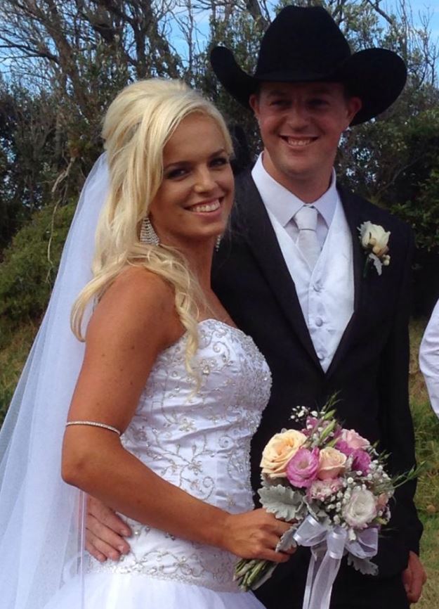 A blonde woman in a wedding dress and a man in a hat and suit.