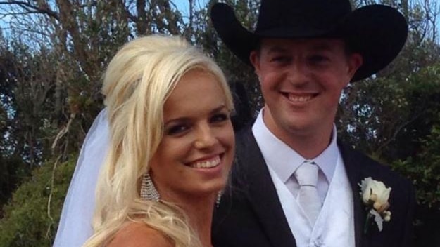 A blonde woman in a wedding dress and a man in a hat and suit.