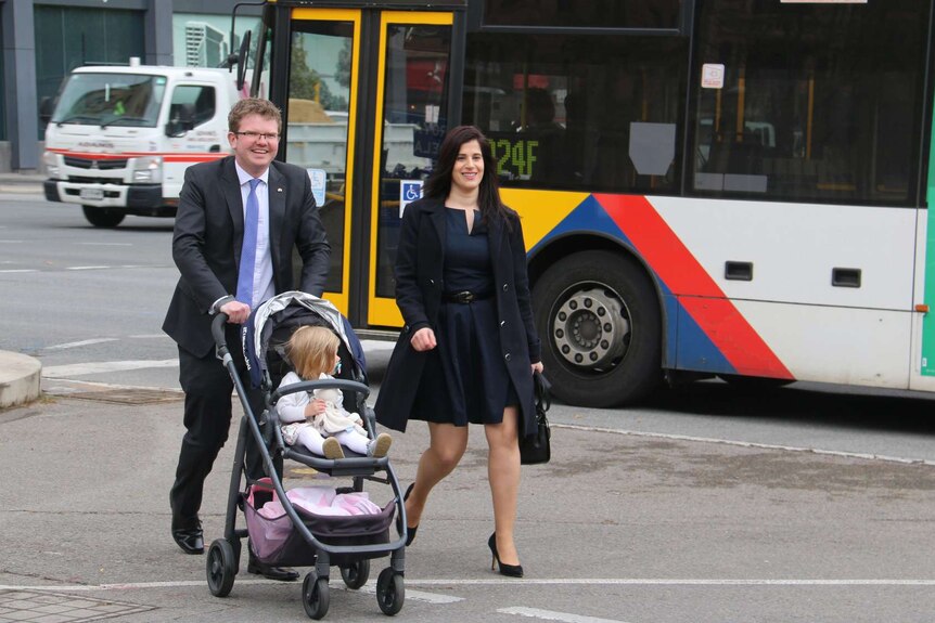 A man in a suit wheels a pram.