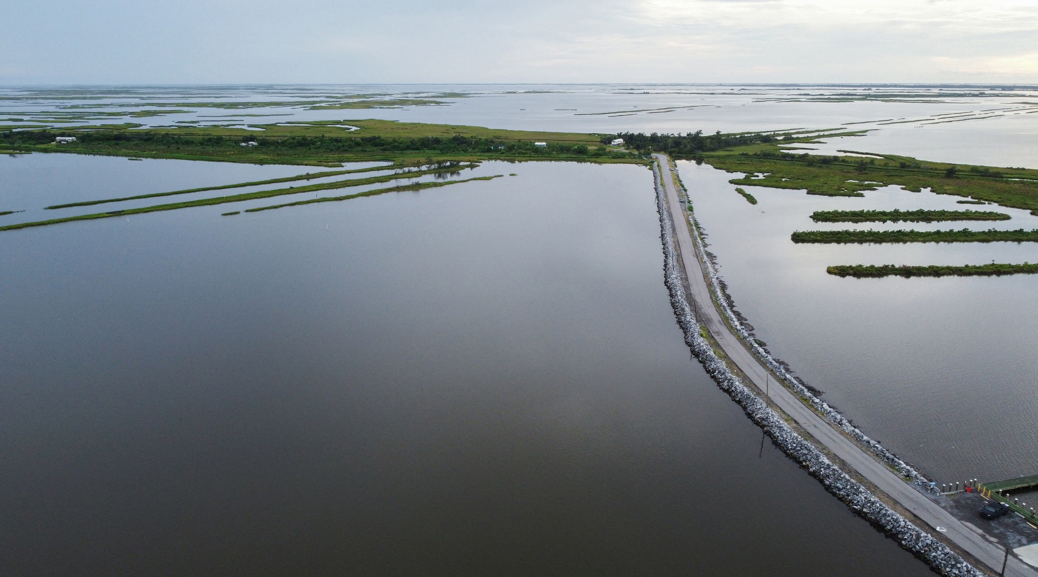an aerial view of land submerged in water with a road running through it and patches of grassy land