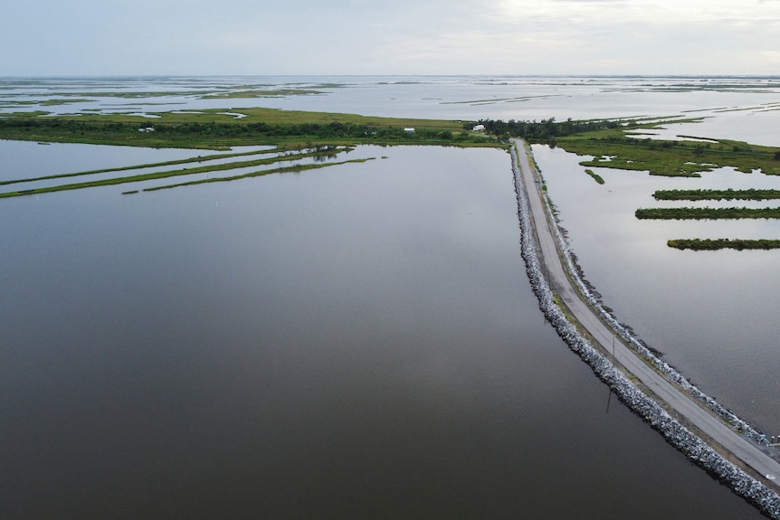 an aerial view of land submerged in water with a road running through it and patches of grassy land