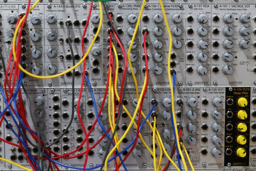 Red, yellow and blue cords and dials on electronic music equipment.