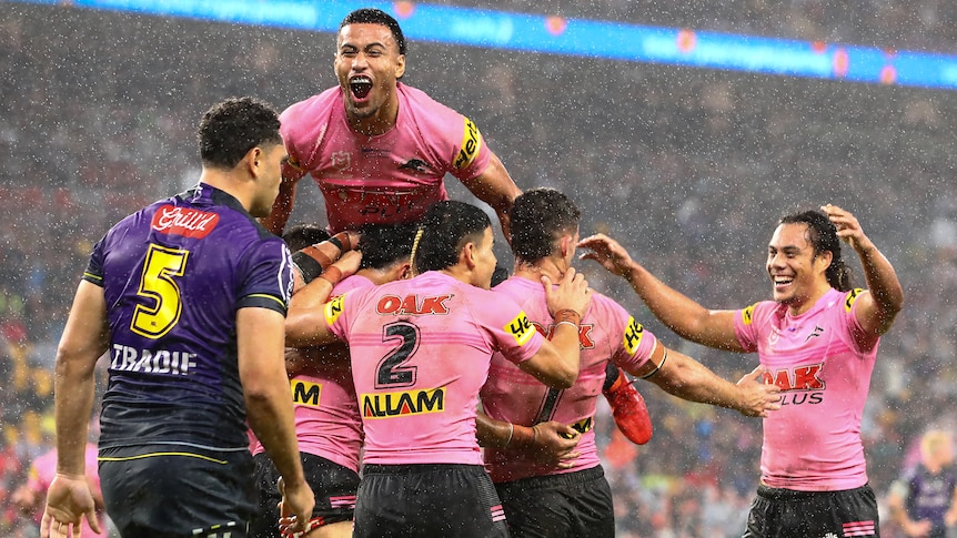 Stephen Crichton jumps on a pack of Penrith Panthers in the rain against the Melbourne Storm.