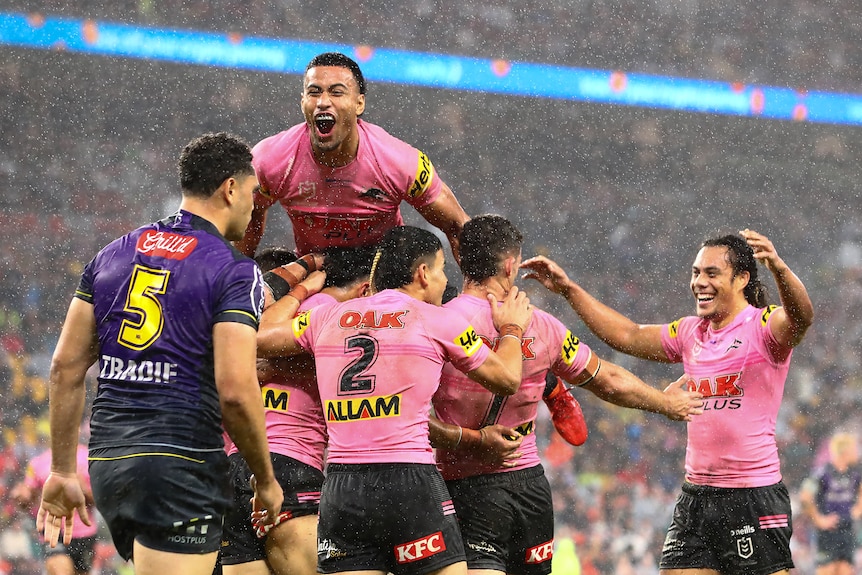 Stephen Crichton jumps on a pack of Penrith Panthers in the rain against the Melbourne Storm.