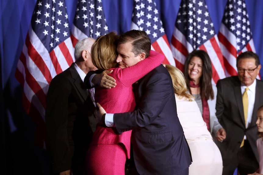 Ted Cruz hugs Carly Fiorina on stage, with US flags behind them.