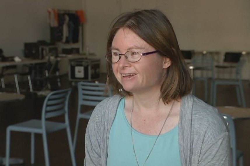 A mid-shot of Julia Hales sitting down and smiling, wearing a blue shirt and grey cardigan.