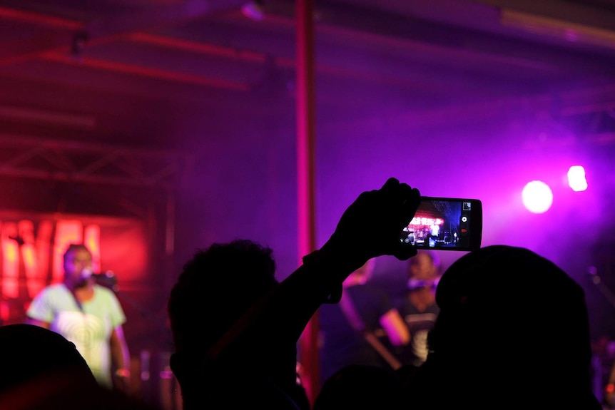 A photo of crowds beneath red stage lights at Barunga Festival.