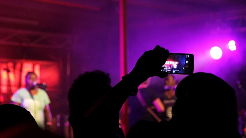 A photo of crowds beneath red stage lights at Barunga Festival.