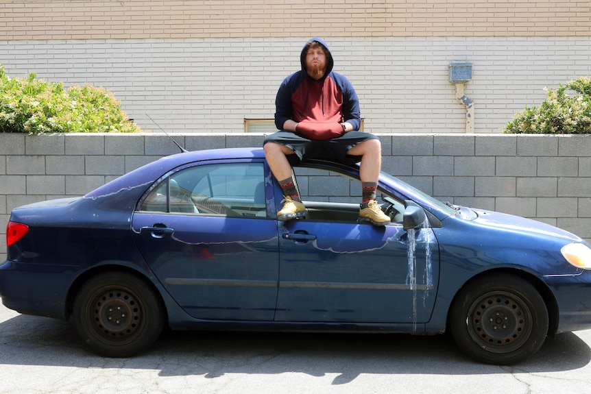 Glauber Contessoto sits on a car