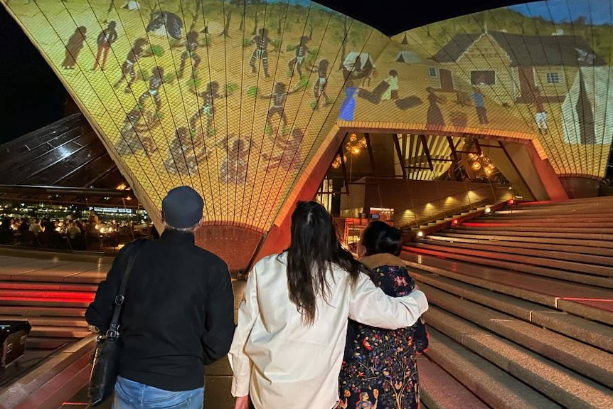 A man and two women look at art being projected onto the Sydney Opera House