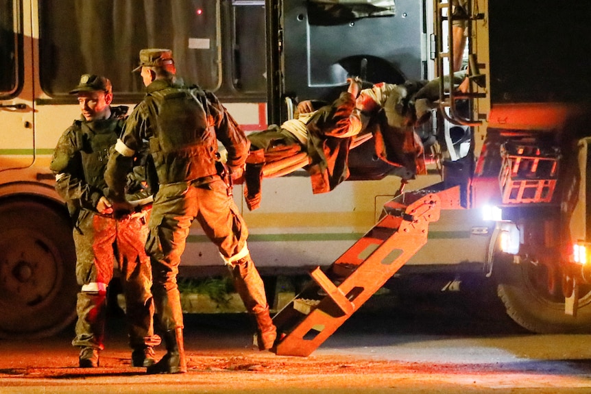 Rannego żołnierza ukraińskiego wynoszono na noszach przed autobus.