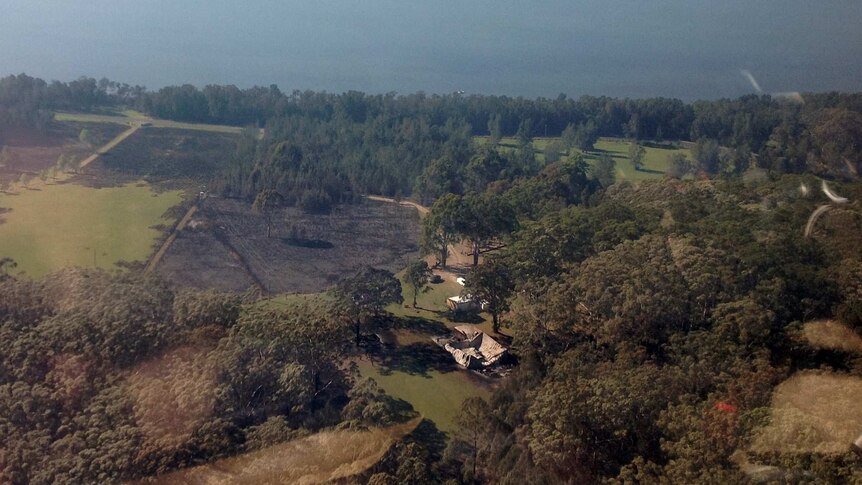 Aerial shot of charred ground and burnt shed from bushfire at Shallow Bay