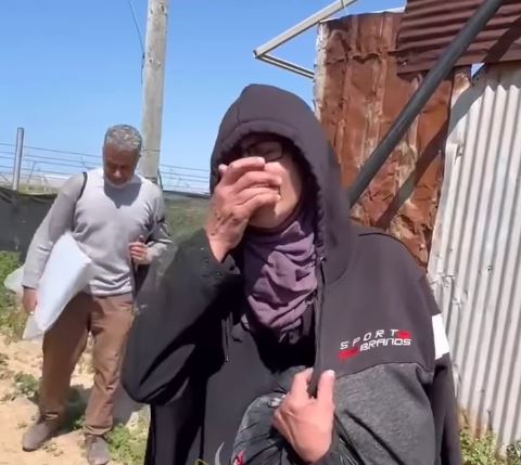 A woman covers her face as she cries