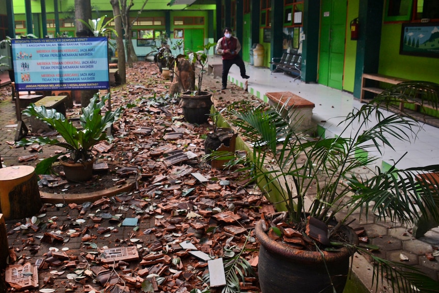 tiles litter the ground at a school with a man standing in the background