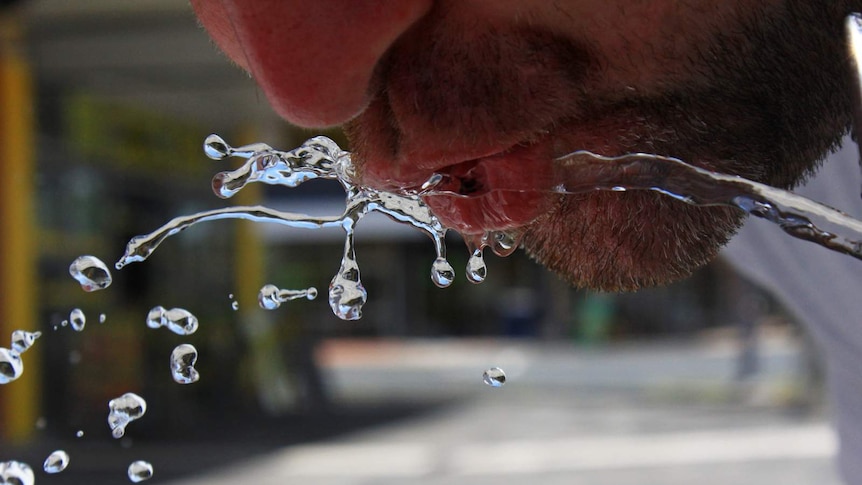 Person drinking from a water cooler