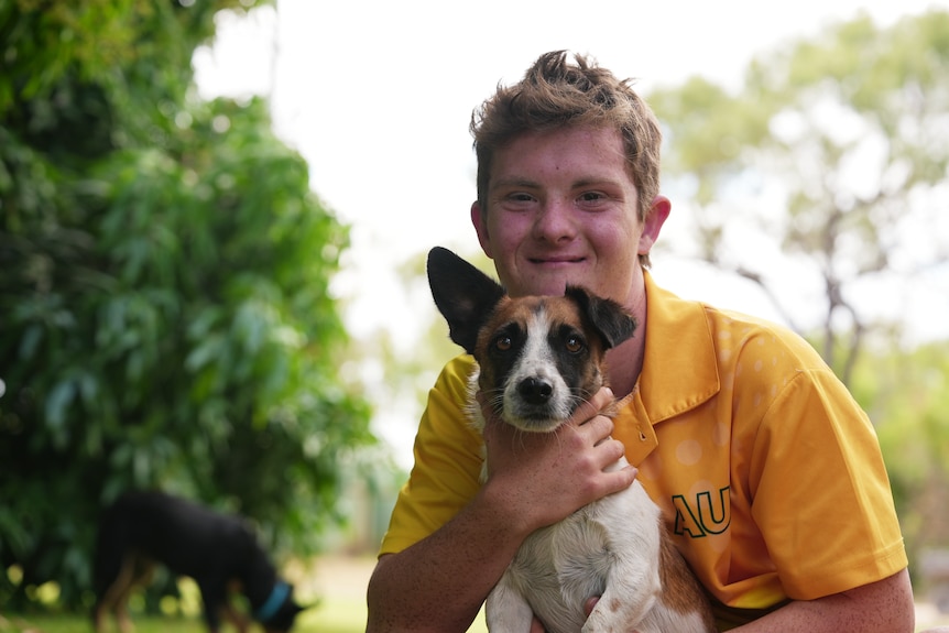 A boy smiling holding a dog.