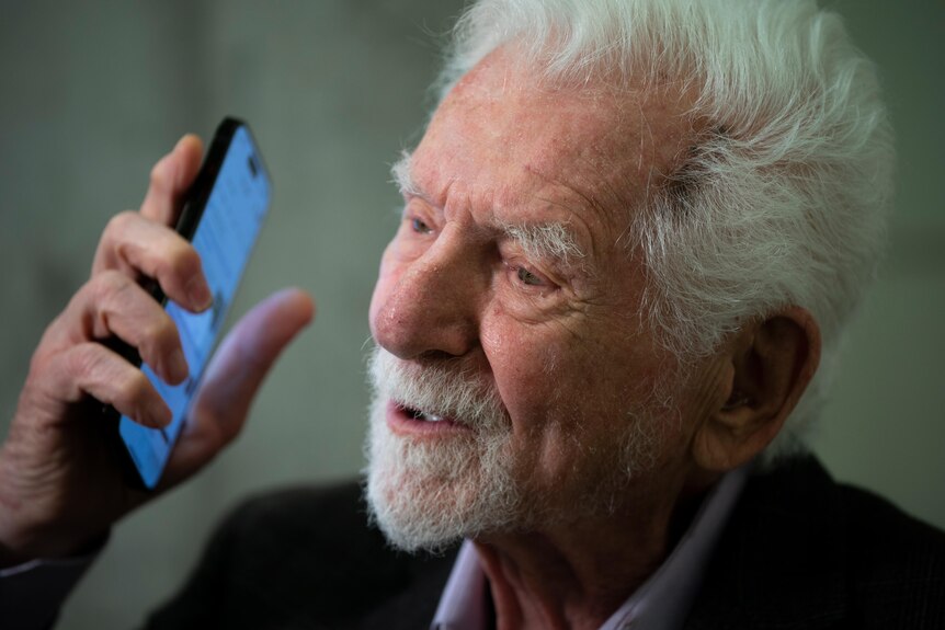 An elderly man poses with a smarphone