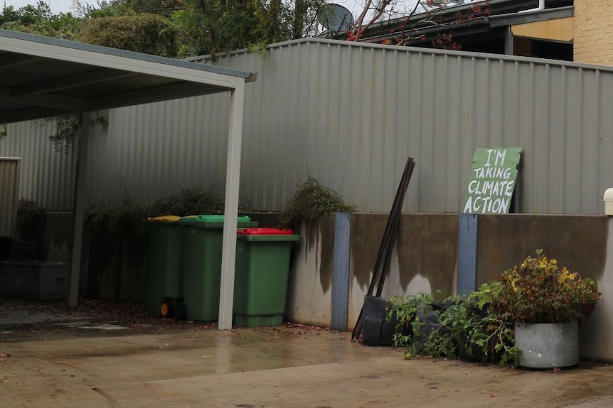 A driveway with bins and a sign that says I'm taking climate action