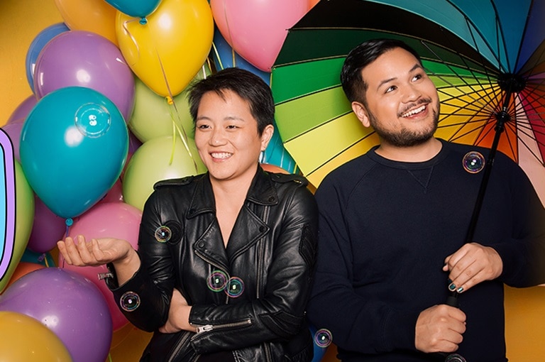 A podcast tile with a photo of two people in front of a rainbow background.