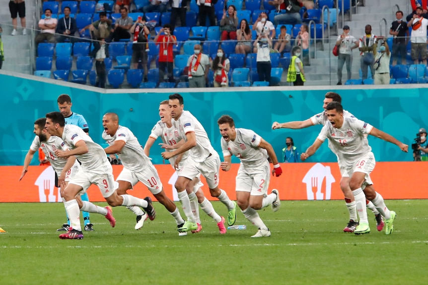 Spain players in white shirts scream and run forwards in a line