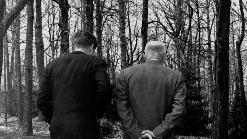 John F Kennedy and Dwight D Eisenhower walk up a path at Camp David.