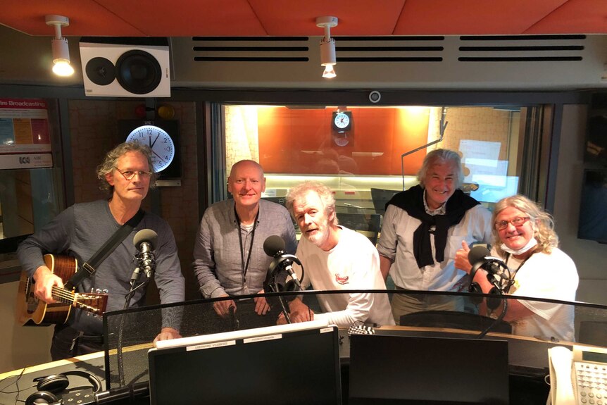 Give men behind microphones in ABC radio studio.