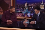 A screen grab of Will Smith and Trevor Noah sitting in a television studio at a desk