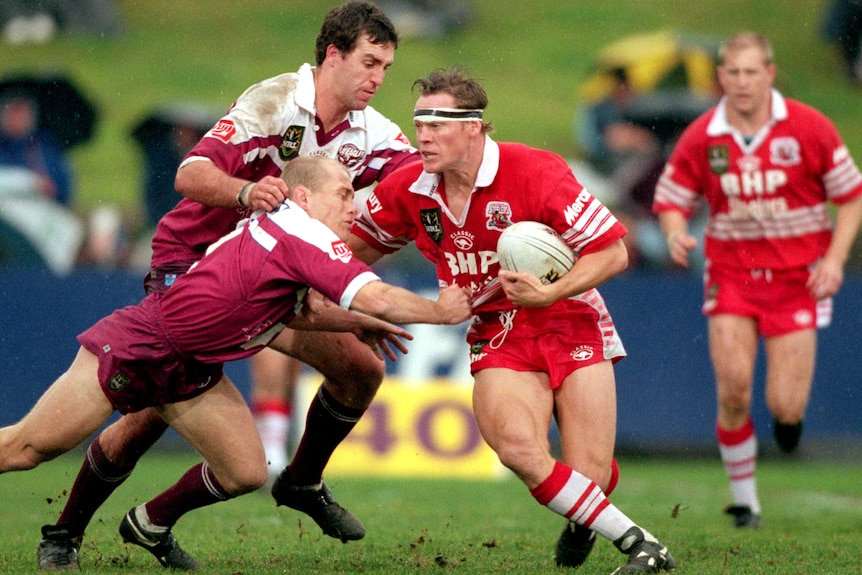 A man runs the ball during an NRL match