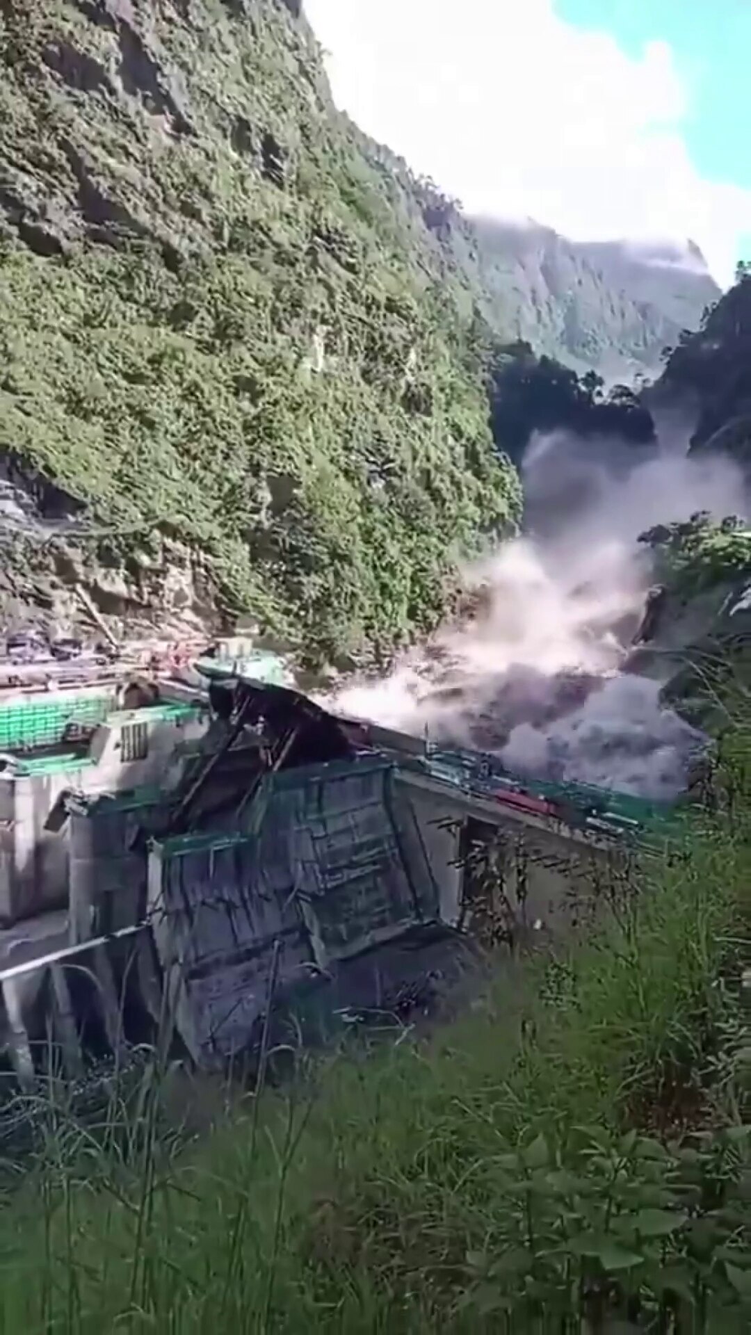 Torrent of murky water engulfs a facility nestled between two mountains.