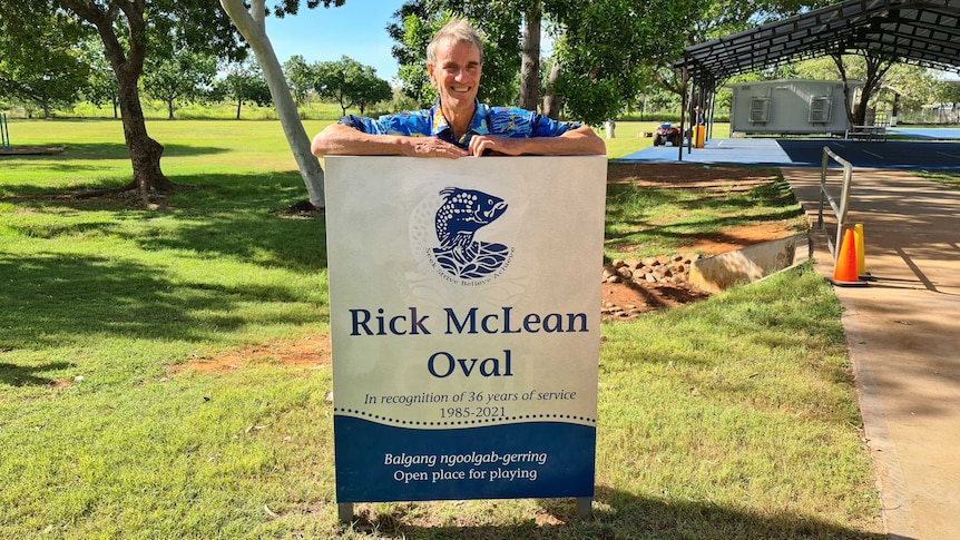 Man smiling above a sign with his name on it. Rick McLean Oval