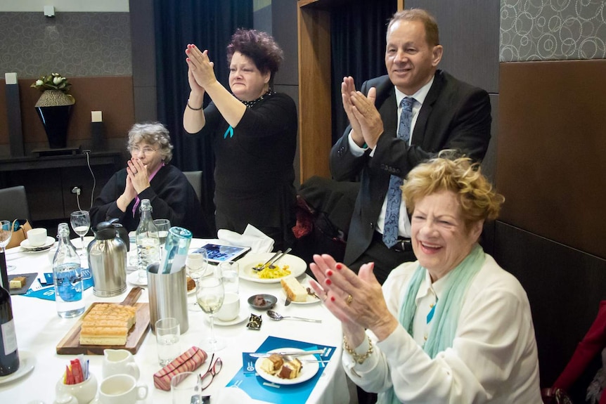 Jill Emberson's family applaud her speech at the National Press Club.