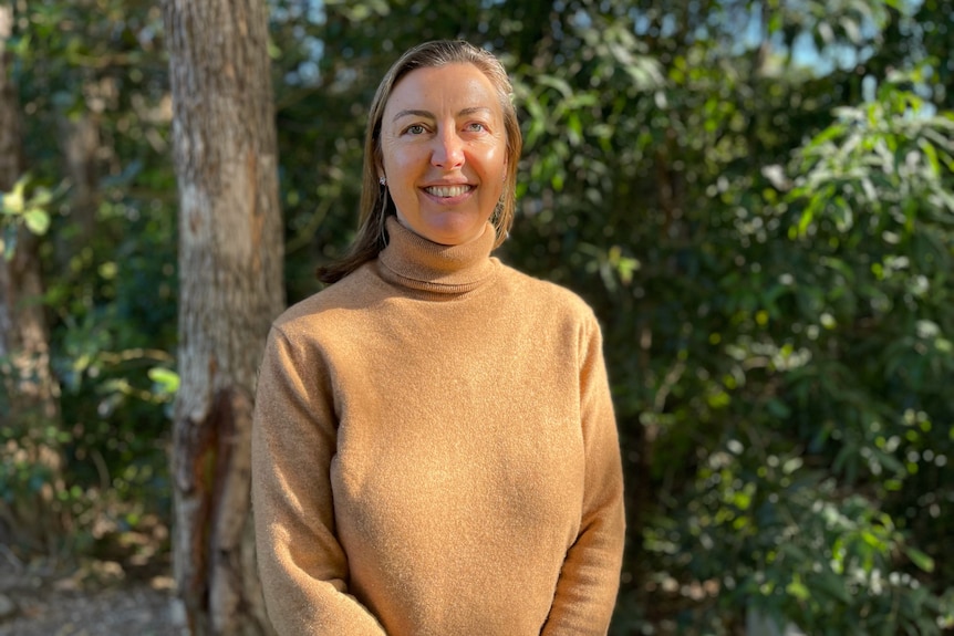 Kathyn Ridge wearing an orange turtleneck, smiling in a portrait taken outdoors.