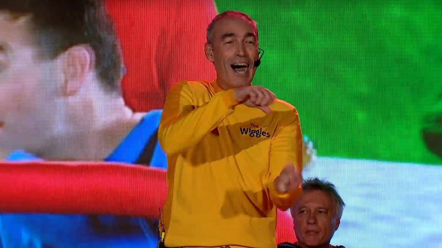 Greg Page wearing a yellow Wiggles costume performing on stage