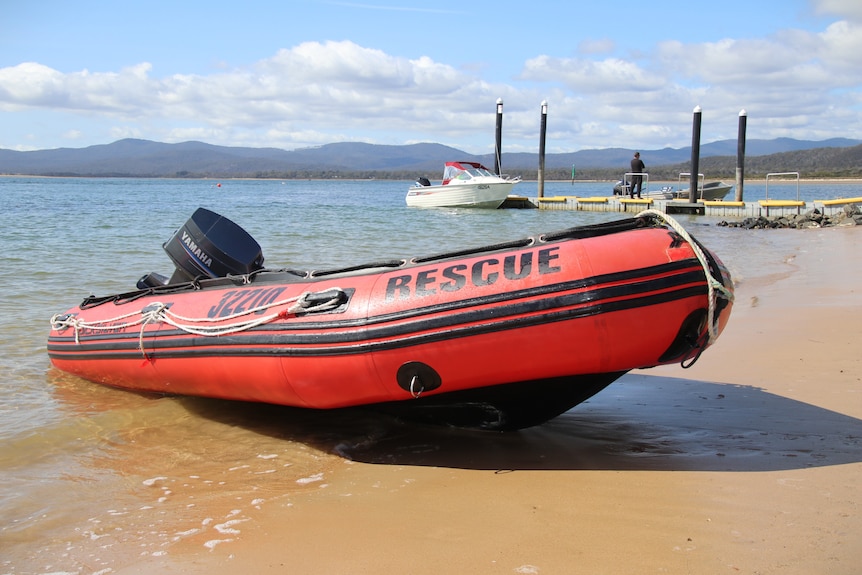 Rescue dinghy at shoreline near a boat ramp.