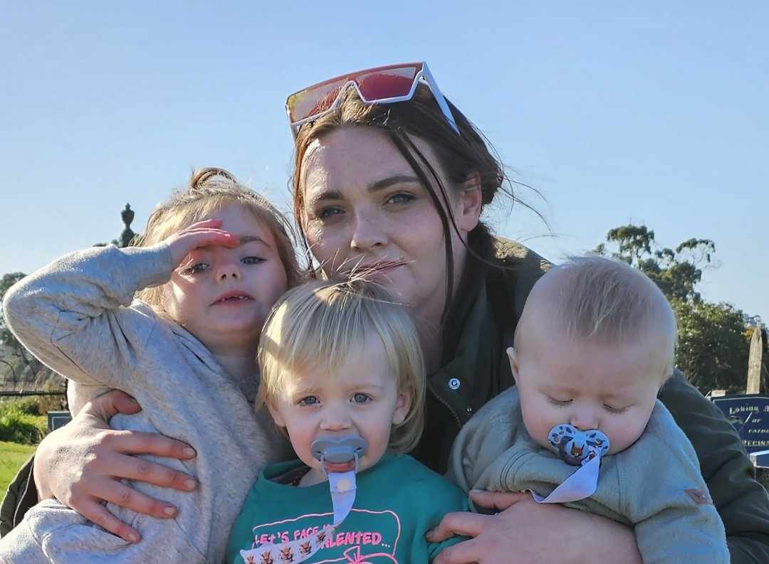 Brunette mother holds two toddlers and a baby