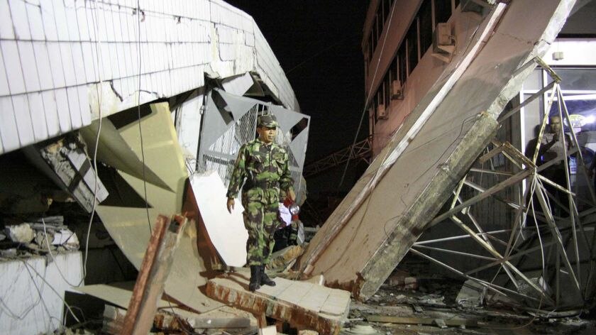 Massive quake: A member of an Indonesian military rescue team walks through a collapsed building in Padang