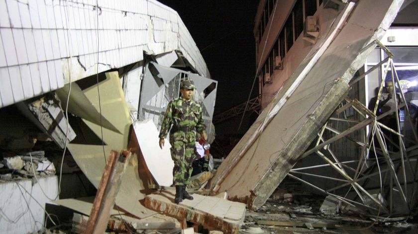 Sumatra earthquake: A member of an Indonesian military rescue team walks through a collapsed building after in Padang