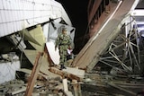 Sumatra earthquake: A member of an Indonesian military rescue team walks through a collapsed building after in Padang