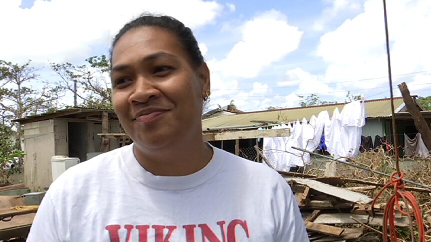 A close shot of Meliana Longopoa with her damaged house in the background.