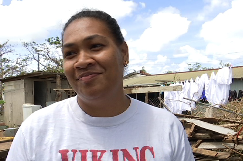 A close shot of Meliana Longopoa with her damaged house in the background.