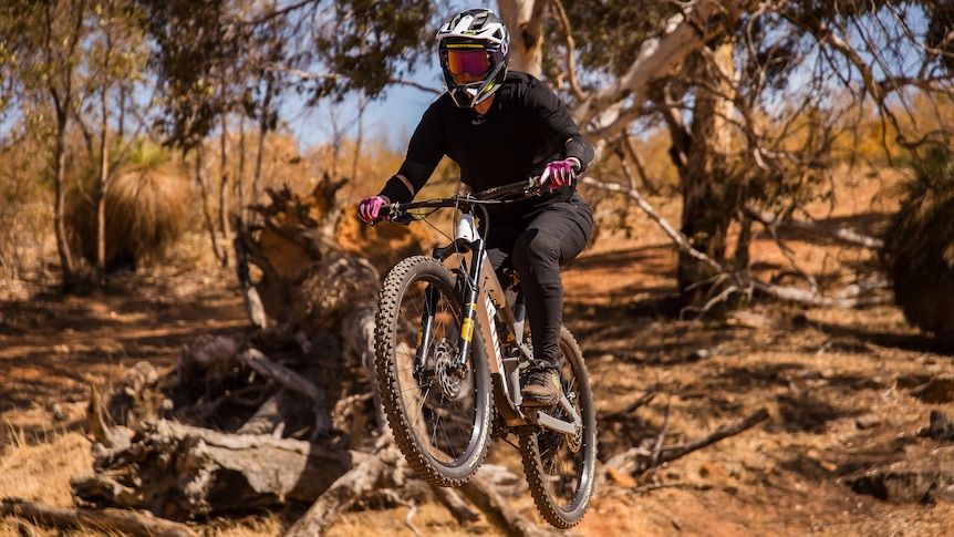 A mountain bike rider in safety gear does a jump.