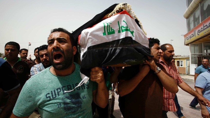Iraqi men carry a coffin during a funeral procession for the victims of a suicide bombing