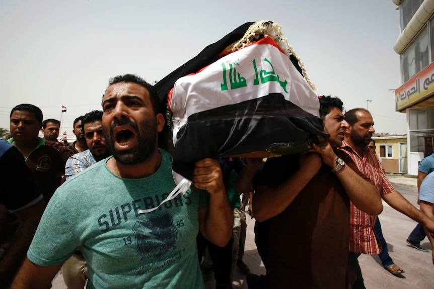 Iraqi men carry a coffin during a funeral procession for the victims of a suicide bombing