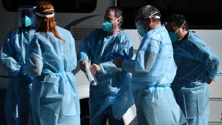 a group of healthcare workers outdoors in protective clothing