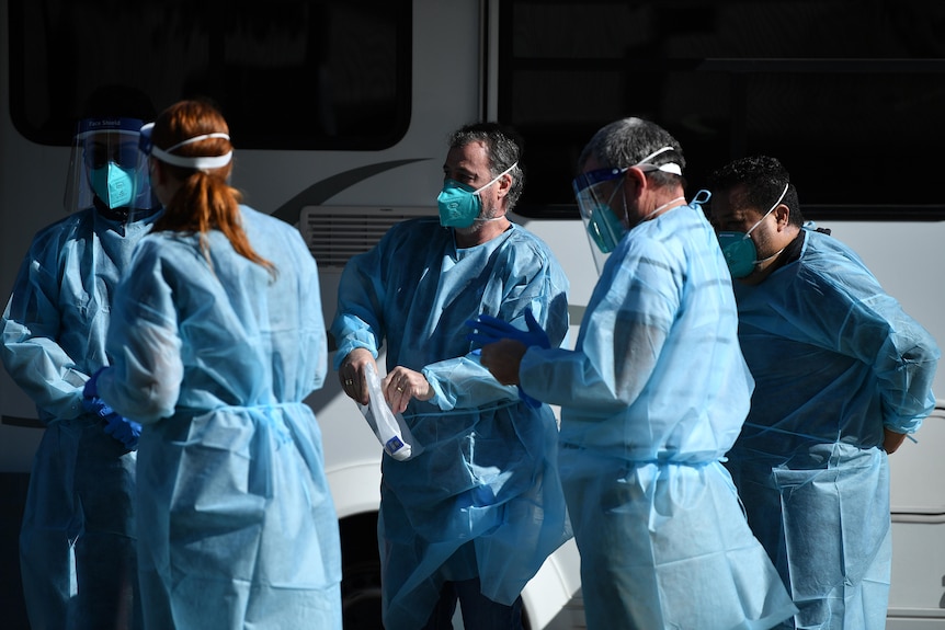 a group of healthcare workers outdoors in protective clothing