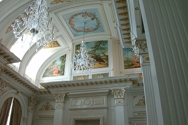 A ceiling featuring huge crystal chandeliers and paintings around the moldings 