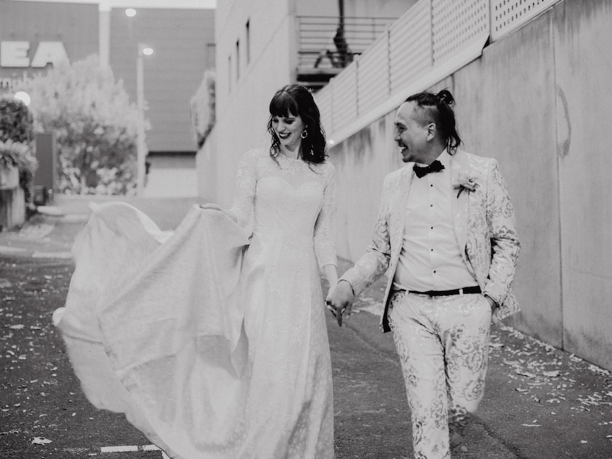 A black and white photo of a young bride and groom walking.