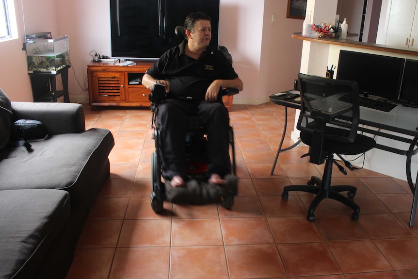 Mark Moodie moves through his living room in a wheelchair