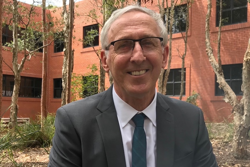 Close up of a man wearing a suit and glasses.