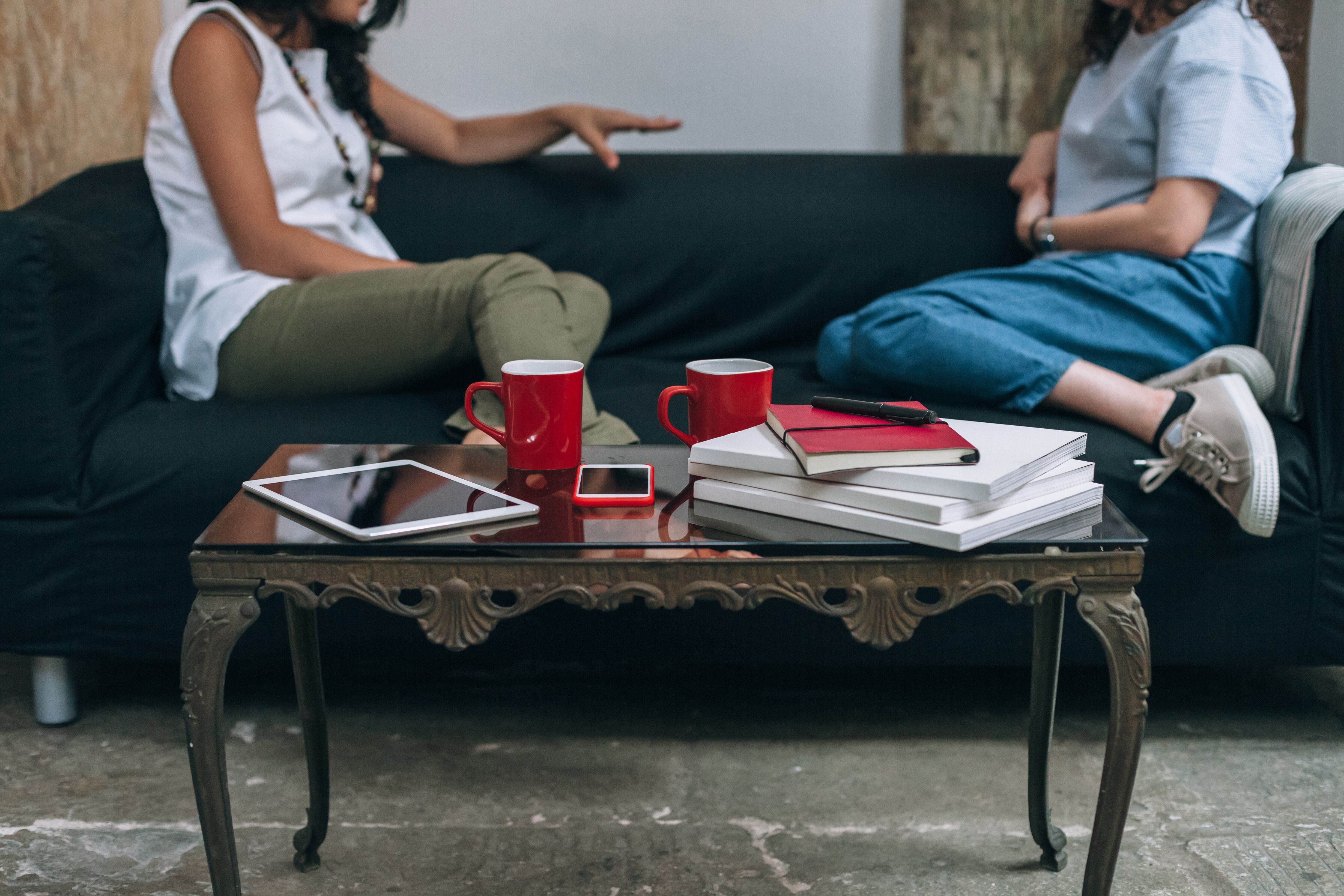 two women sit on a couch chatting